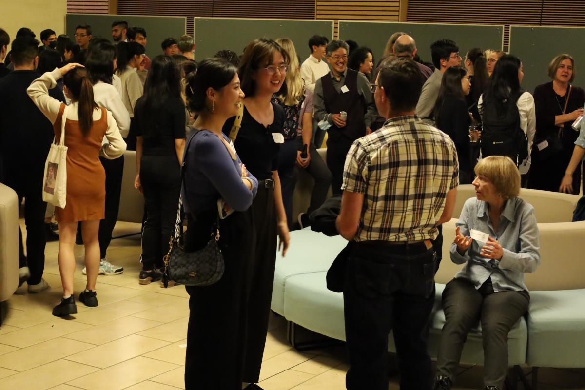 Photo of attendees standing and talking at the event.